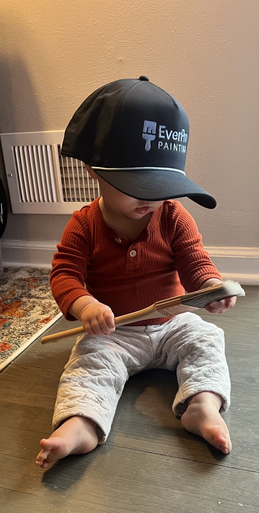 Ethan's son in an oversized EverPro Painting hat holding a paintbrush