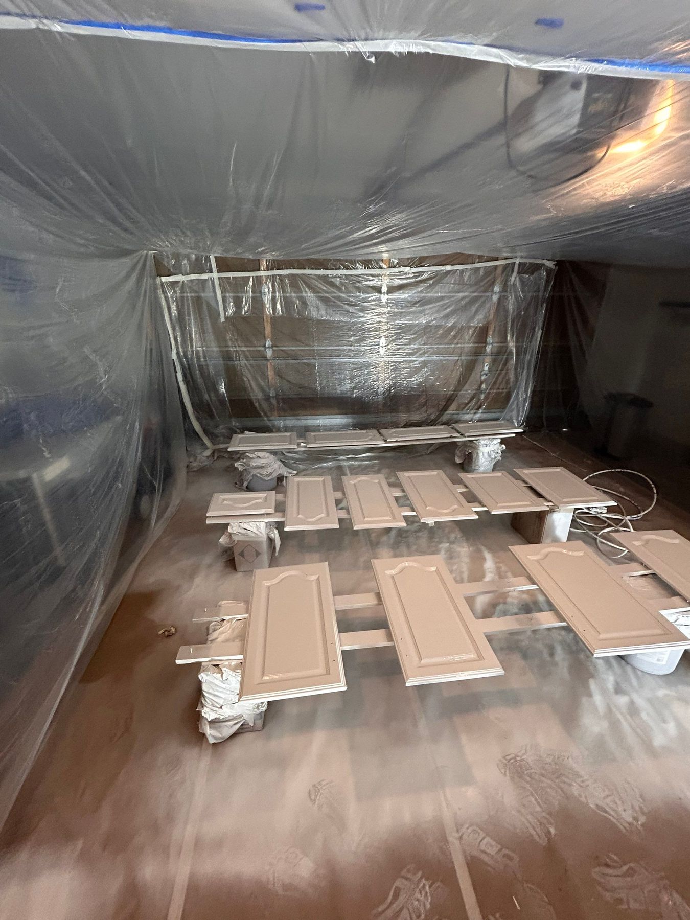 Enclosed on-site spray booth built in the garage — cabinet doors laid out for fine finish spraying