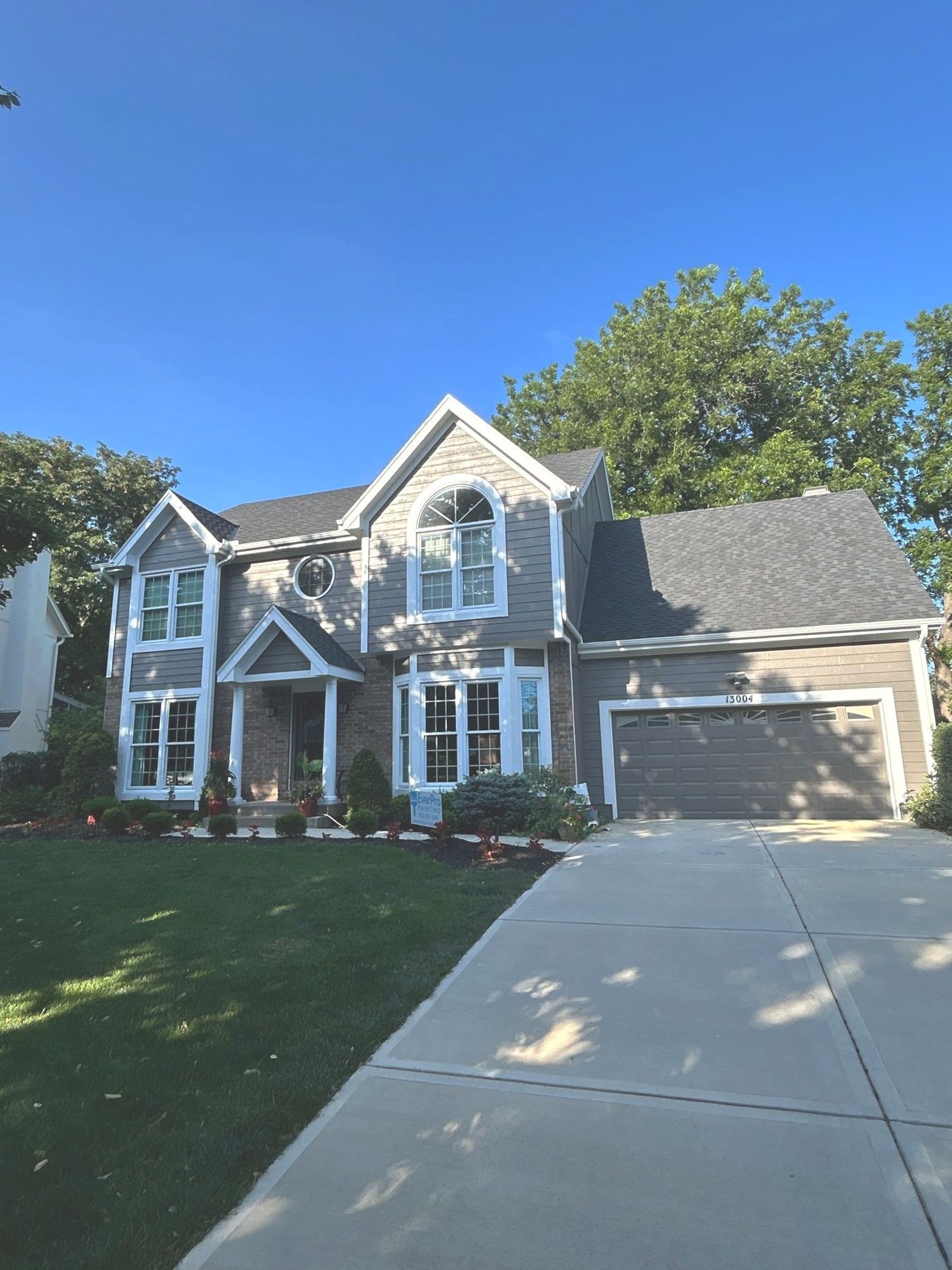Finished exterior house painting job in Kansas City — gray siding with bright white trim over brick