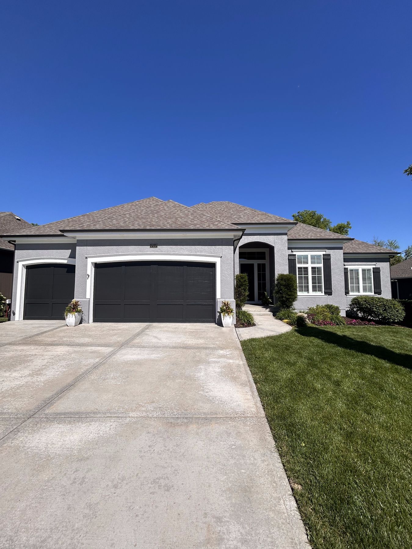 Overland Park stucco home repainted light gray with black accents by EverPro Painting