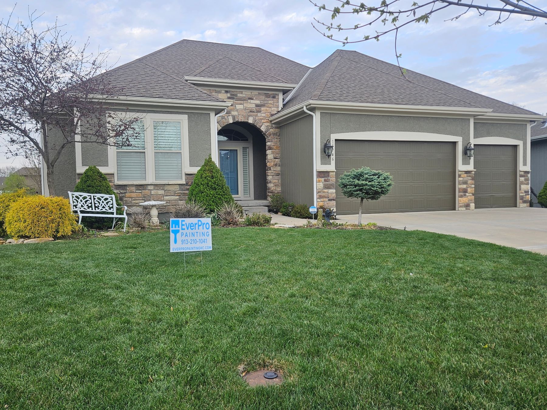 Finished exterior paint job in Kansas City — sage stucco and stone home with EverPro Painting yard sign