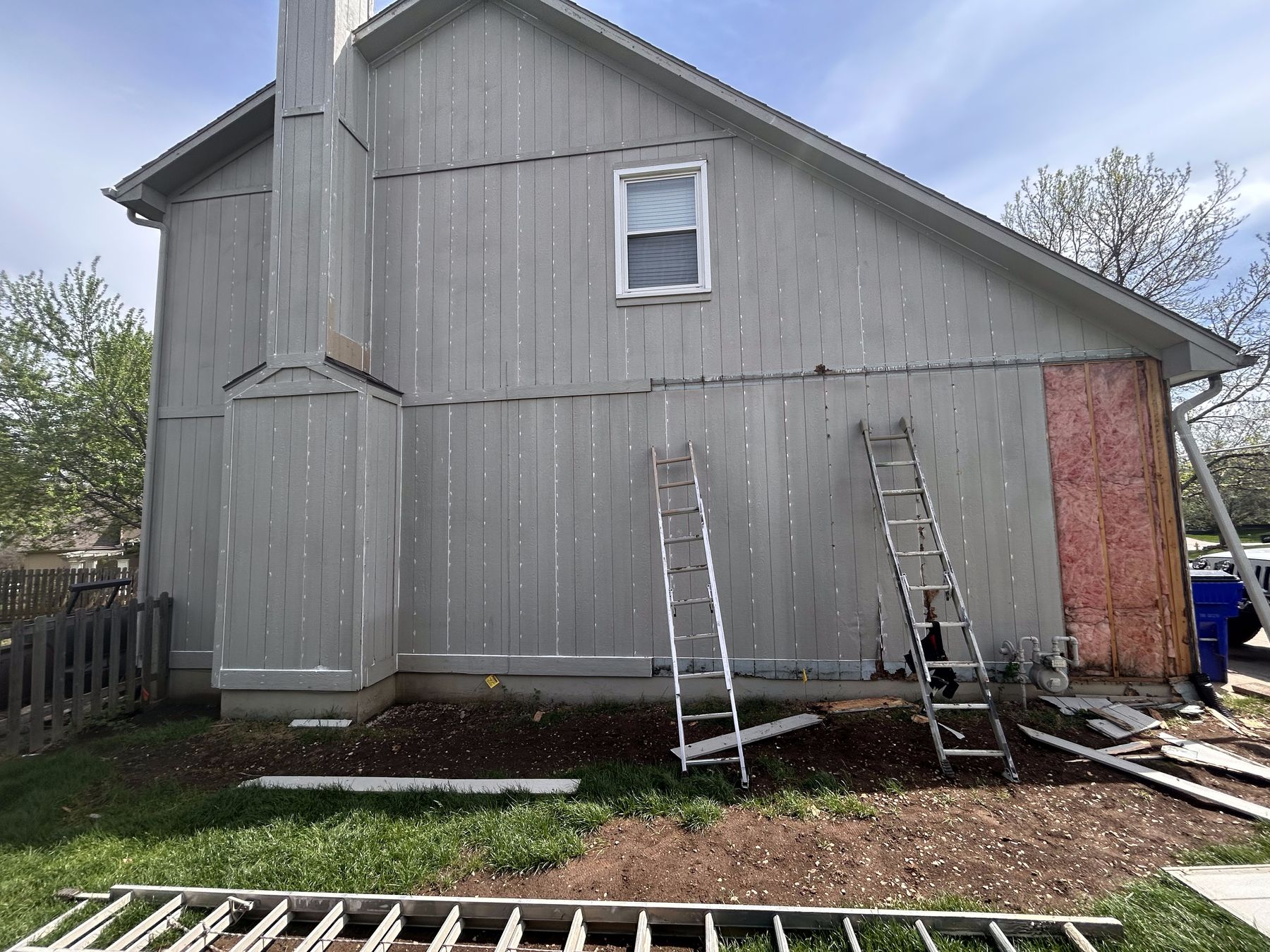 Wood rot repair in progress โ damaged siding removed down to the insulation before replacement and painting
